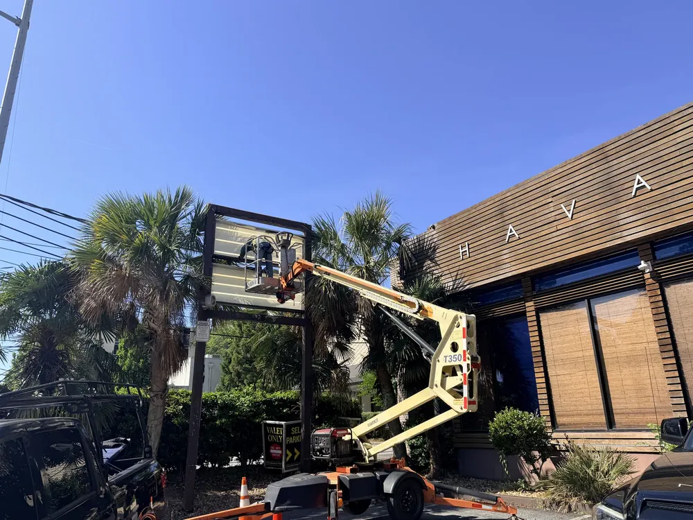 Boom lift positioning a sign panel on site