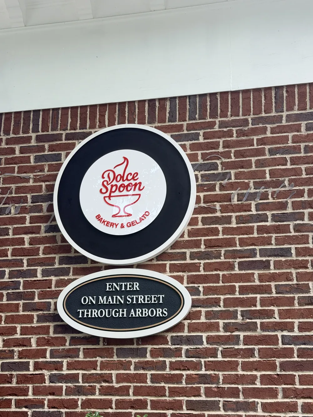 Dolce Spoon round blade sign on a brick wall
